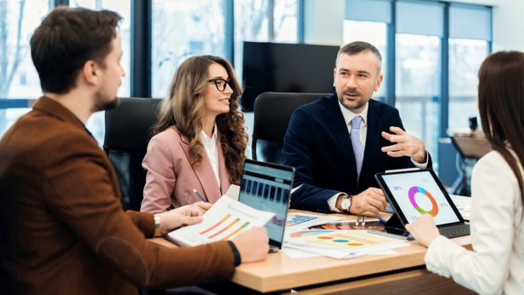 Consultoria empresarial analisa gráficos e indicadores em reunião estratégica com equipe executiva.