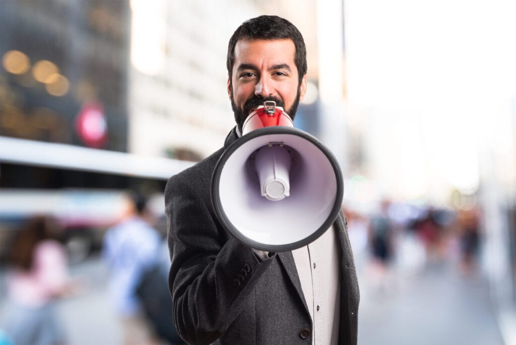 Homem usando megafone, remetendo a promoção para atrair clientes.