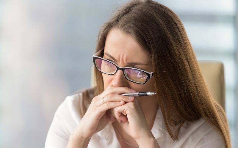 Worried businesswoman sitting alone in office. Pensive middle-aged woman resting her head on hands and looks aside in window. Concentrated female entrepreneur frowning thinking about problem solution