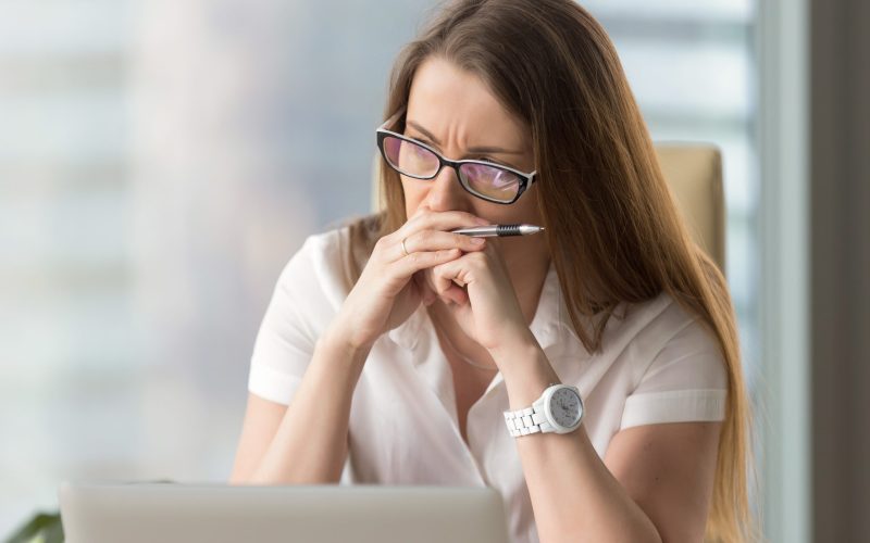 Worried businesswoman sitting alone in office. Pensive middle-aged woman resting her head on hands and looks aside in window. Concentrated female entrepreneur frowning thinking about problem solution